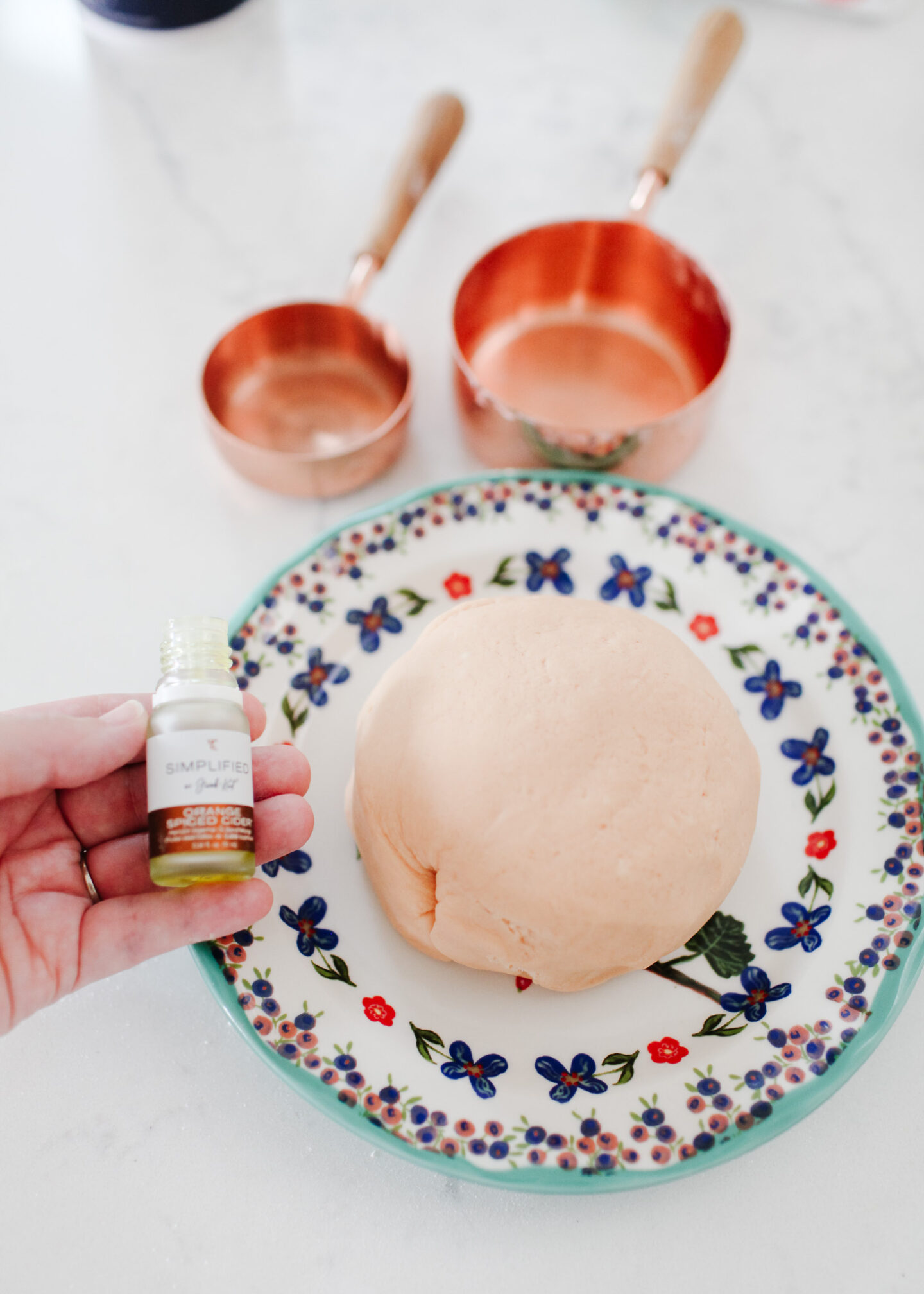 Homemade orange playdough on plate with essential oil