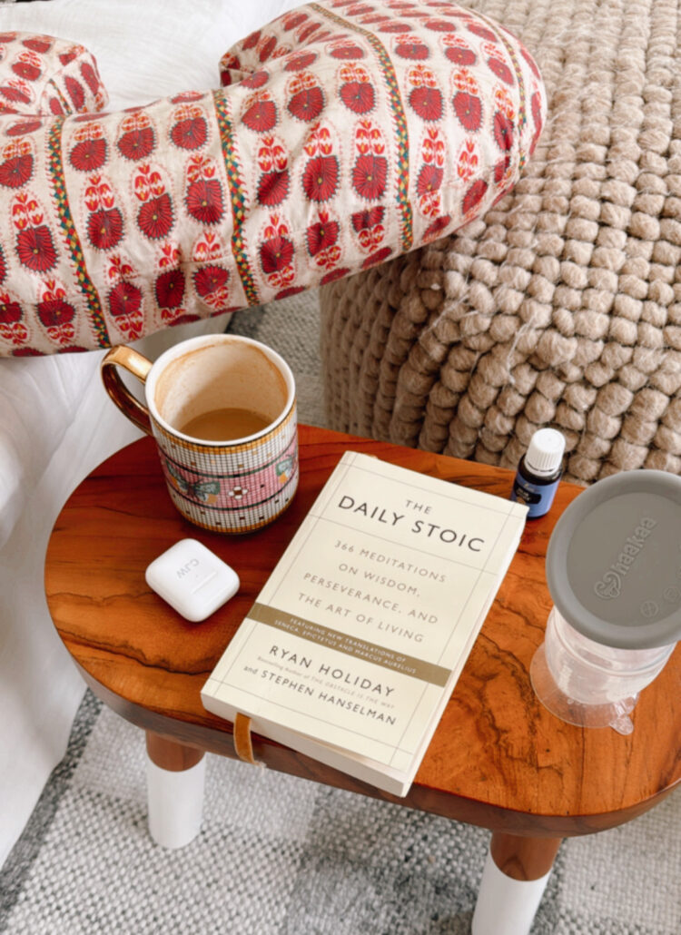 the daily stoic book, coffee, EarPods, hakaa breast pump, boppy pillow in living room